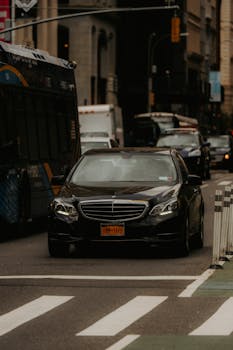 Black Mercedes-Benz parked on city street amidst traffic in urban setting.