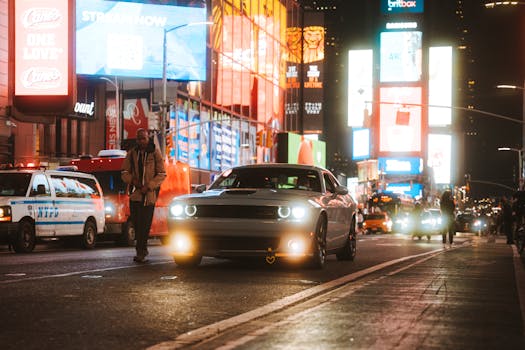 Dynamic Times Square at night featuring cars, pedestrians, and illuminated billboards.