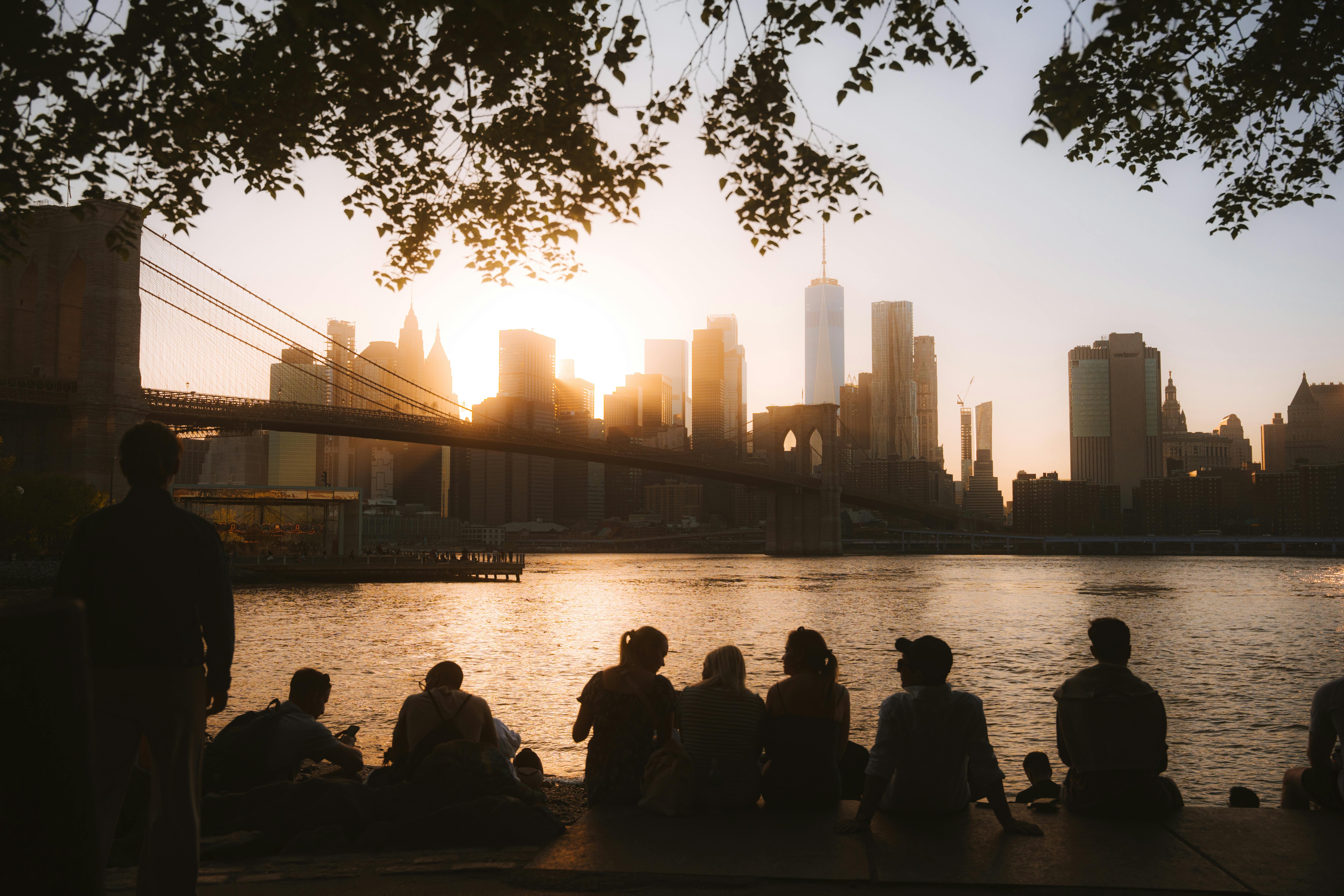 Silhouetted group enjoying a sunset view of the Brooklyn Bridge and Manhattan skyline.
