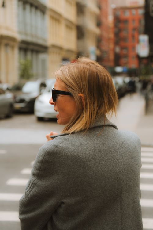 Free A stylish woman in a gray coat crosses a bustling urban street. Stock Photo