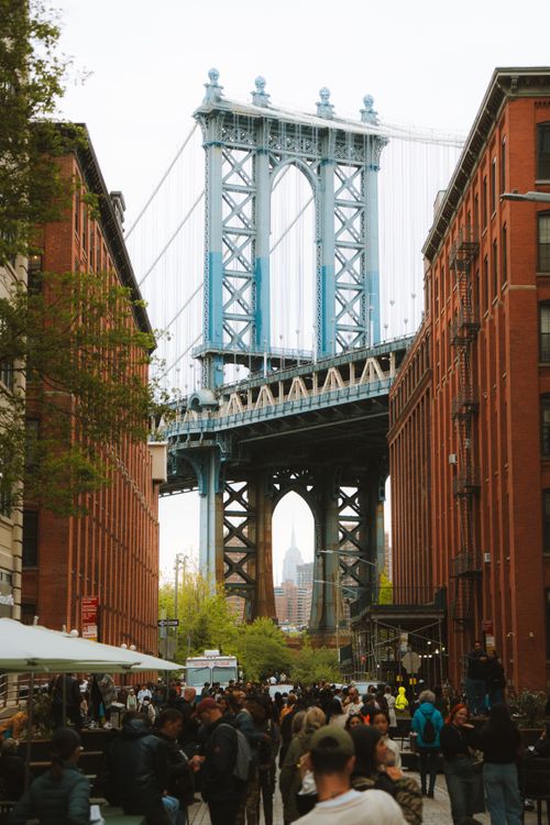 Free Iconic view of the Manhattan Bridge from Dumbo, Brooklyn with people walking the bustling streets. Stock Photo