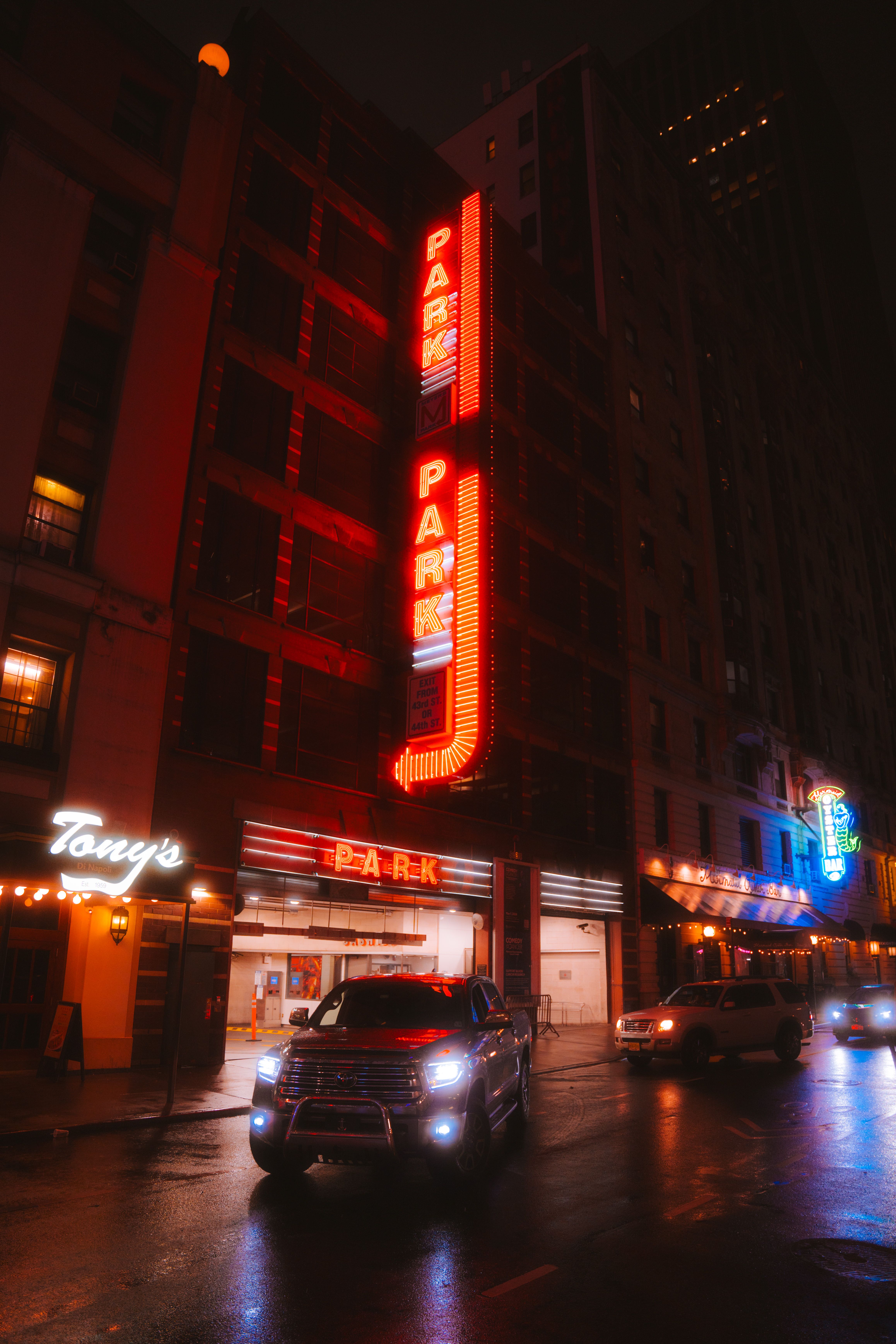 Vibrant city street at night with glowing neon signs and night traffic.