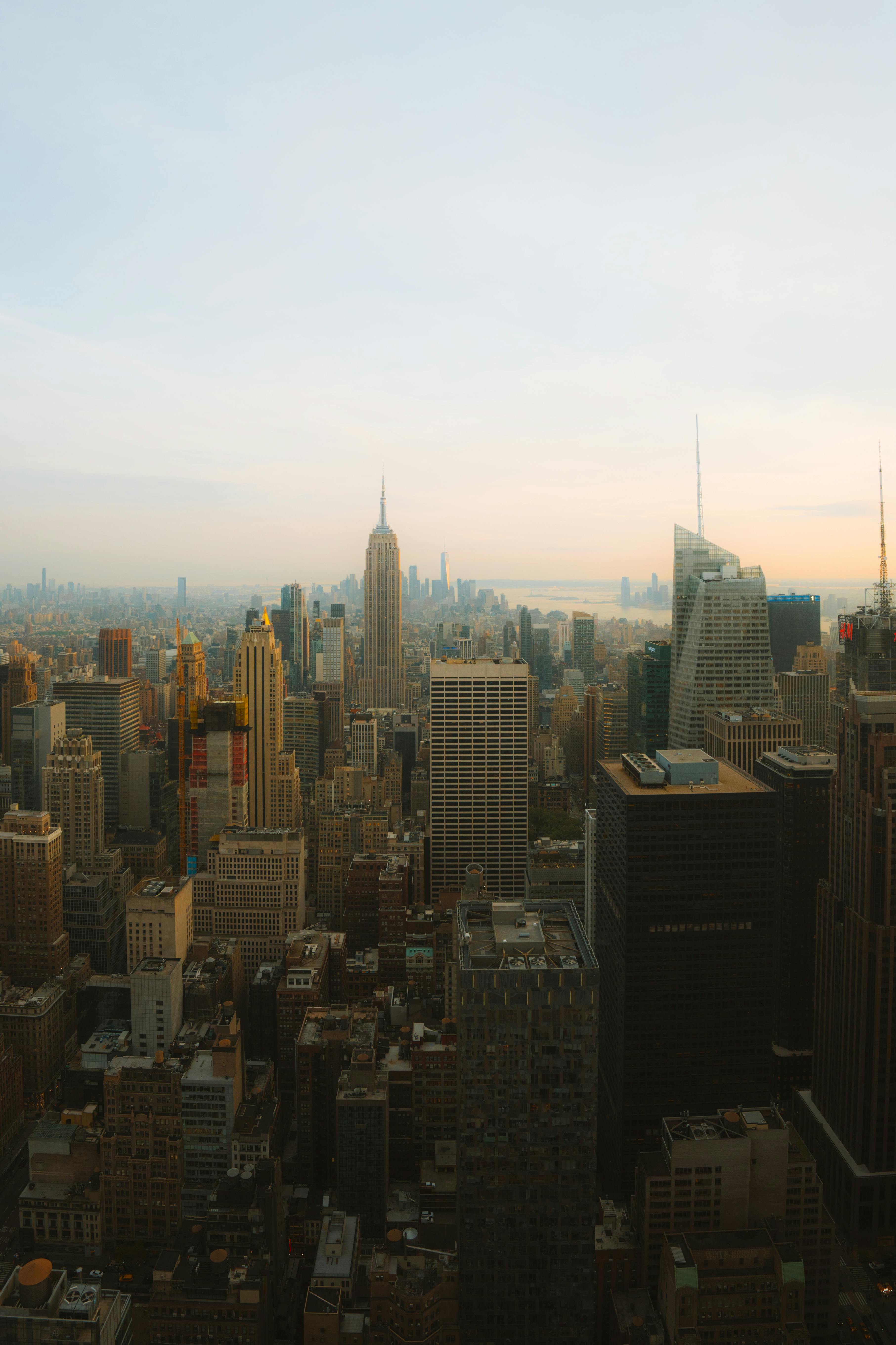 Dusk aerial view of Manhattan skyline highlighting iconic landmarks with a warm sunset glow.