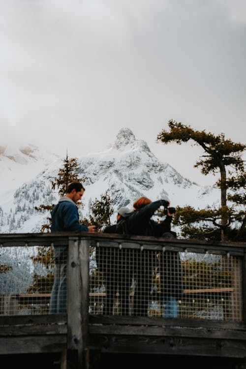People standing on a wooden deck looking at a mountain