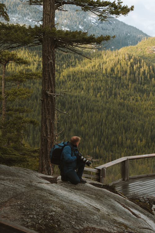 A person with a backpack is sitting on a wooden bridge