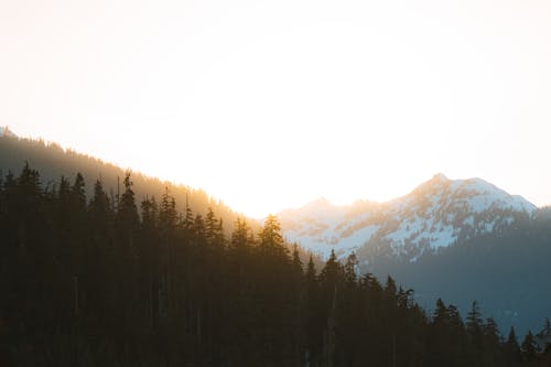 Sun Rising behind Snowcapped Mountains