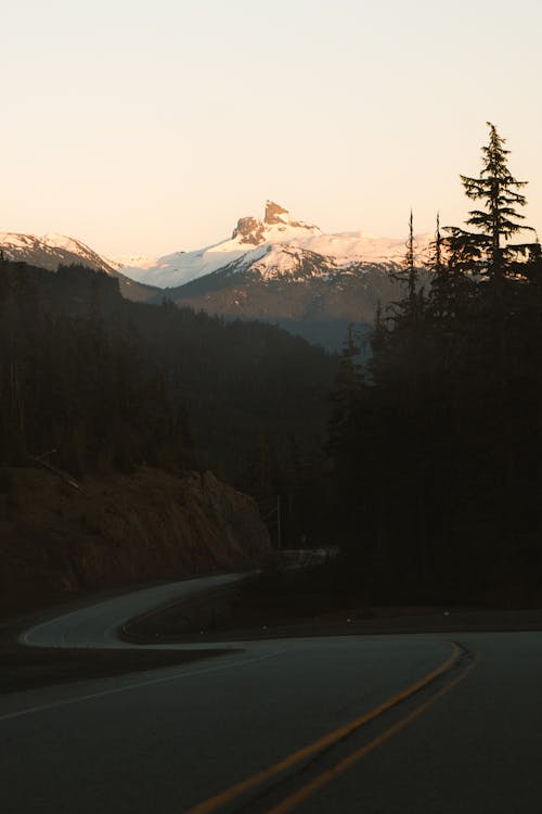 A road with mountains in the background and a car driving down it