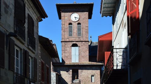 A clock tower is in the middle of a narrow street