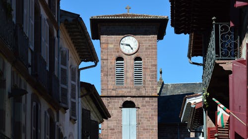 A clock tower is seen in the middle of a city street