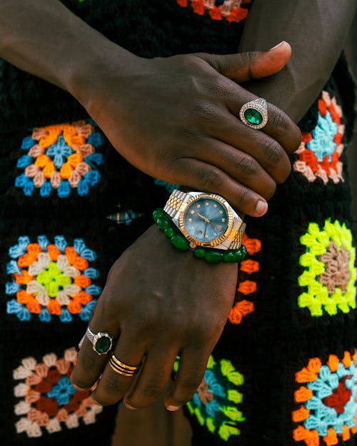 A person wearing a colorful crochet sweater and a watch
