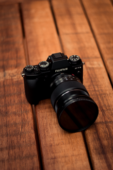A detailed shot of a Fujifilm X-T1 camera with lens on a wooden background.