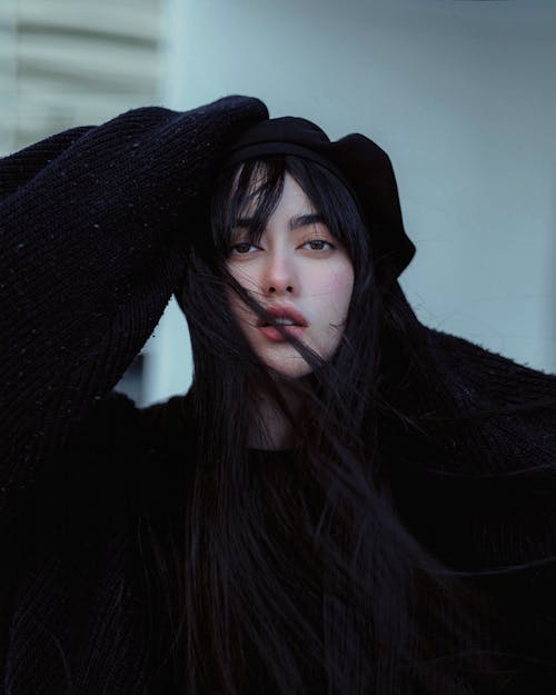 A woman with long black hair wearing a black sweater