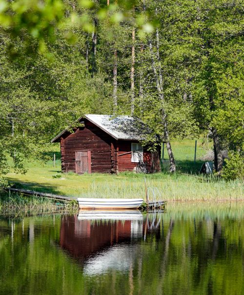 Free Rustic cabin by a serene lake surrounded by lush greenery, perfect for rural retreats. Stock Photo
