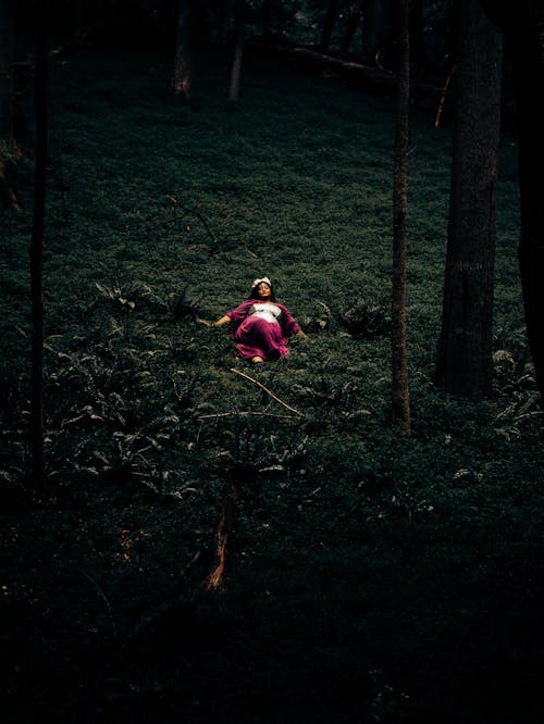 A moody shot of a woman laying  in the woods 