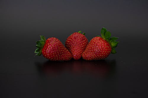 Close-up Photo of Three Red Strawberries on Black Surface