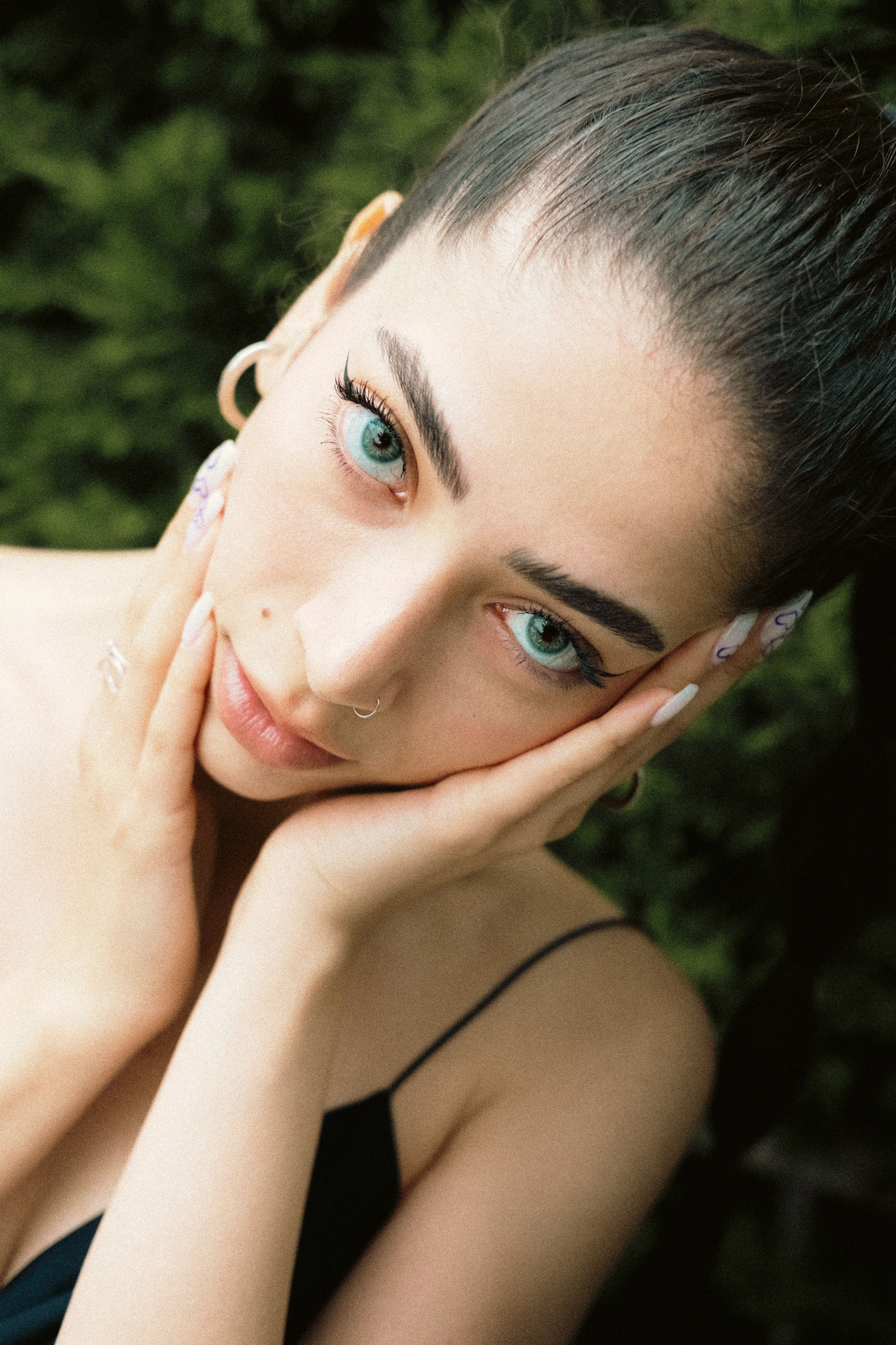 Portrait of a young woman with striking eyes and a nose piercing, outdoors. Perfect for fashion themes.