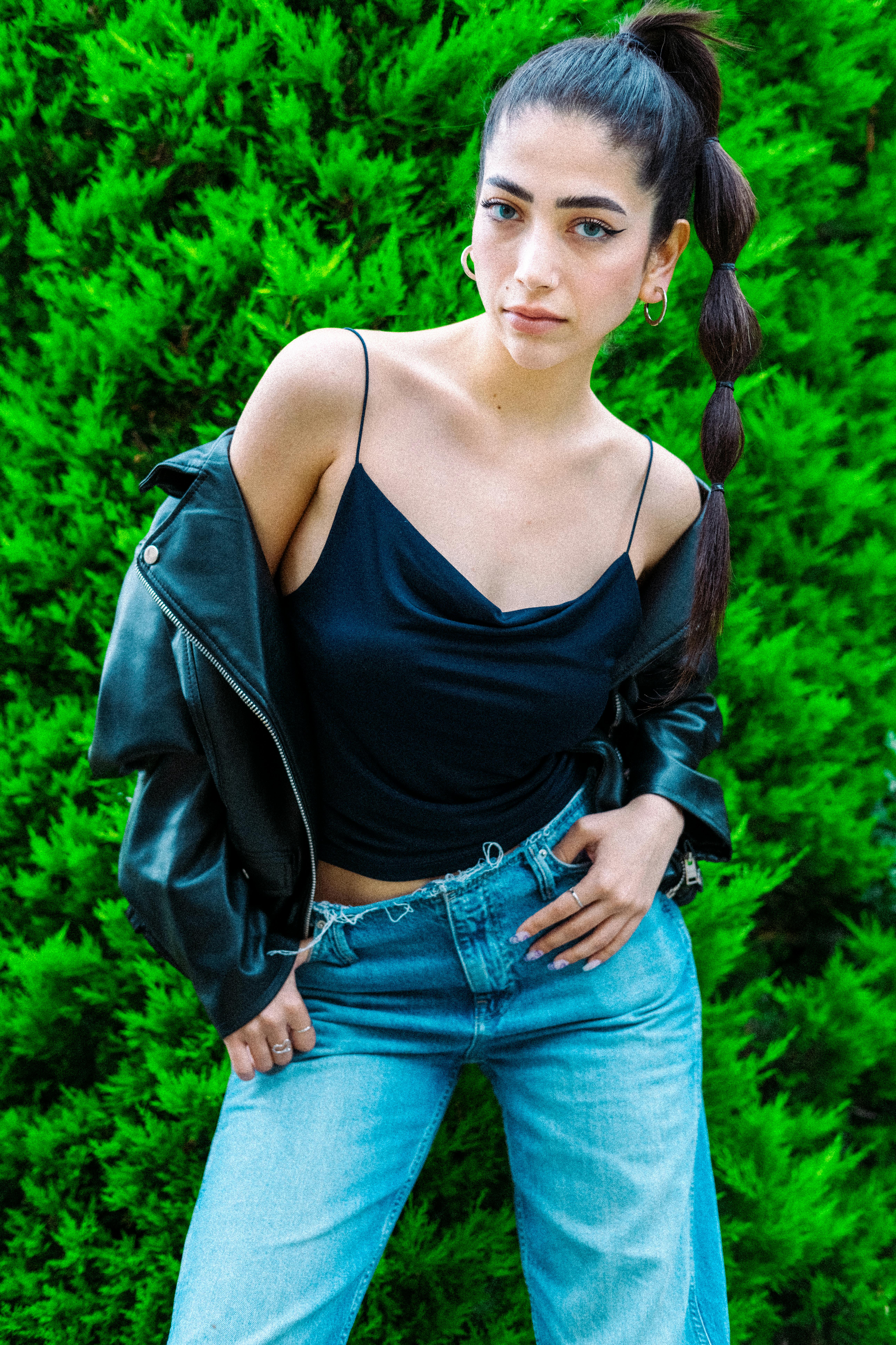 Stylish woman in black top and jeans posing outdoors. Modern fashion photography.