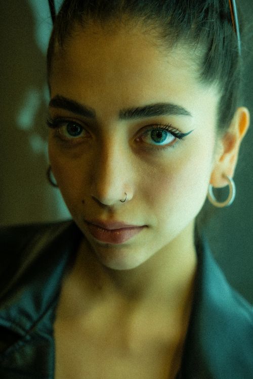 Free Close-up portrait of a woman with earrings and a nose ring, showing a vivid expression. Stock Photo