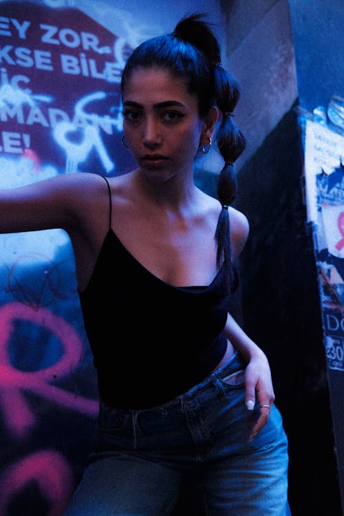 A woman in jeans and a black top posing in front of graffiti