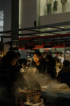 Captivating scene of people at an urban night market enjoying steaming street food.