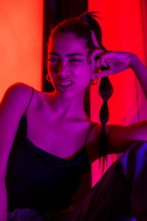 A woman sitting in front of a red and purple light