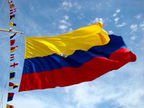 Vibrant Colombian flag waving against a bright blue sky with additional colorful maritime flags.