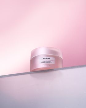 Stylish cosmetic cream jar with pink background, perfect for beauty and skincare themes.