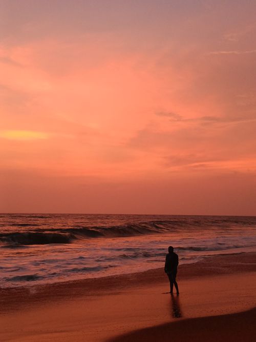 Free A lone silhouette stands on the beach, absorbing a stunning sunset over the ocean. Stock Photo