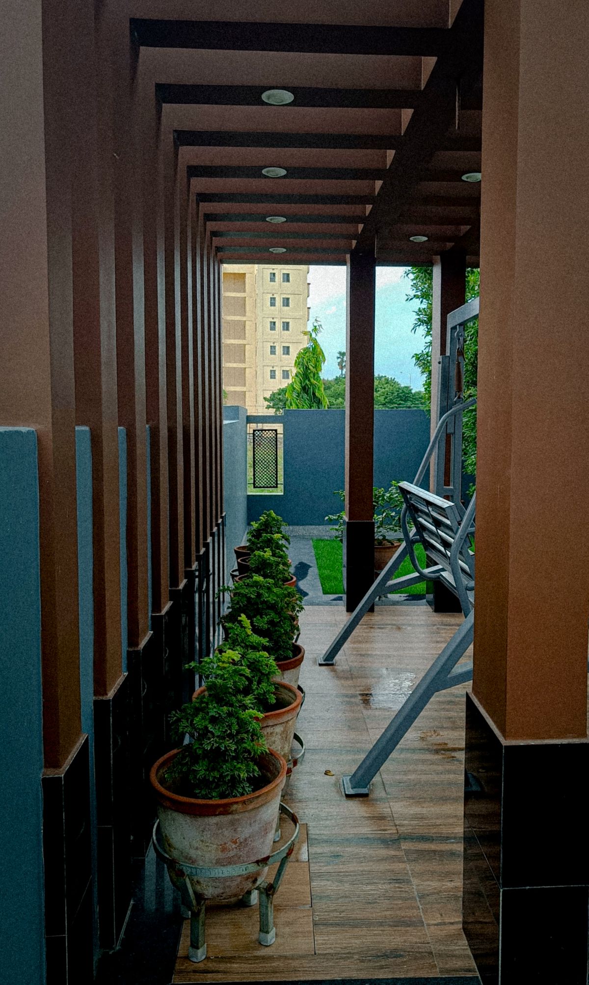 Elegant porch area in Barrackpore, India with potted plants and a swing bench. Stock Photo.