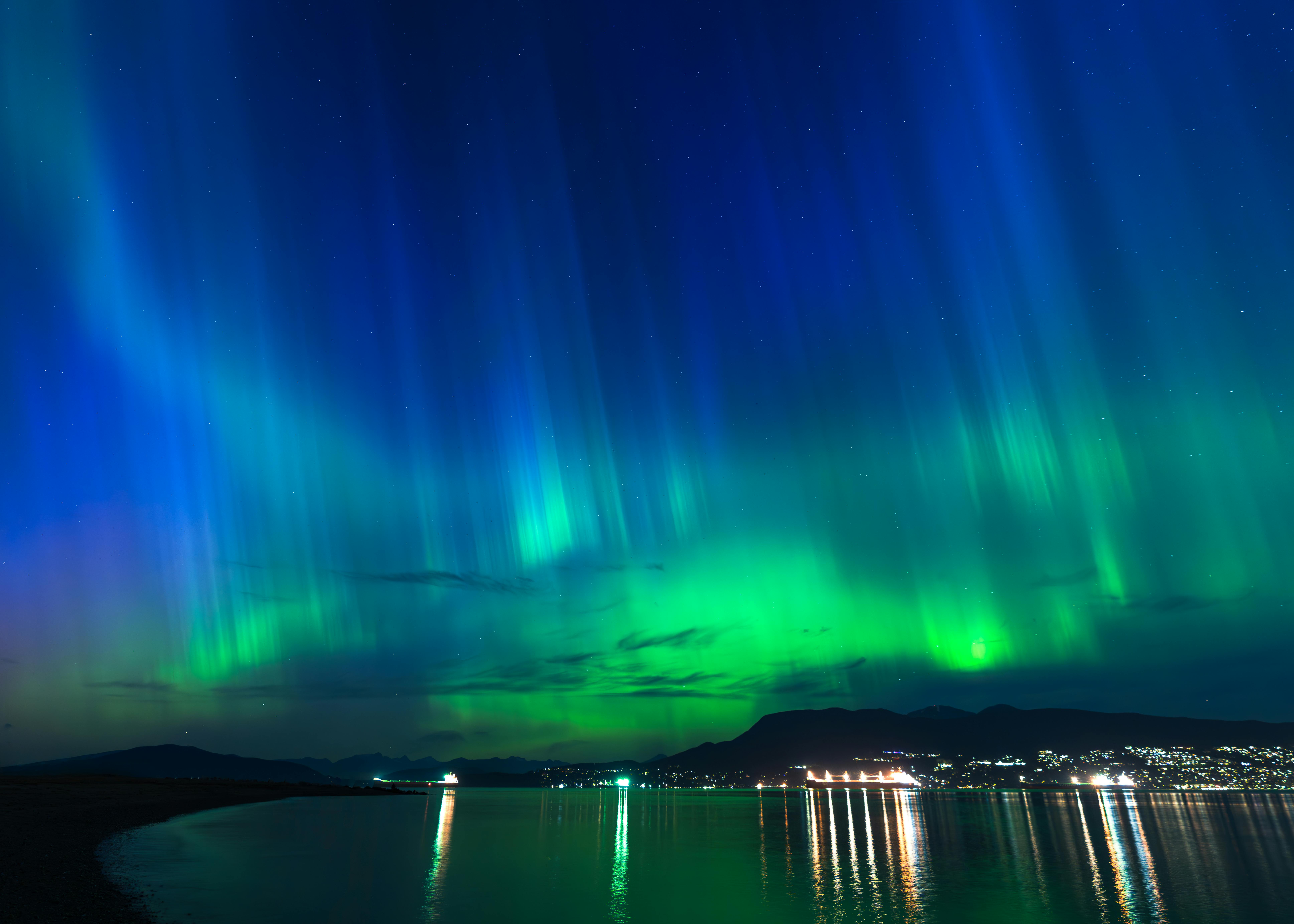 北极光在海边城市上空闪烁，照亮了夜空