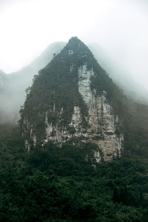 Free A mystical tropical mountain peak shrouded in mist and surrounded by lush greenery. Stock Photo
