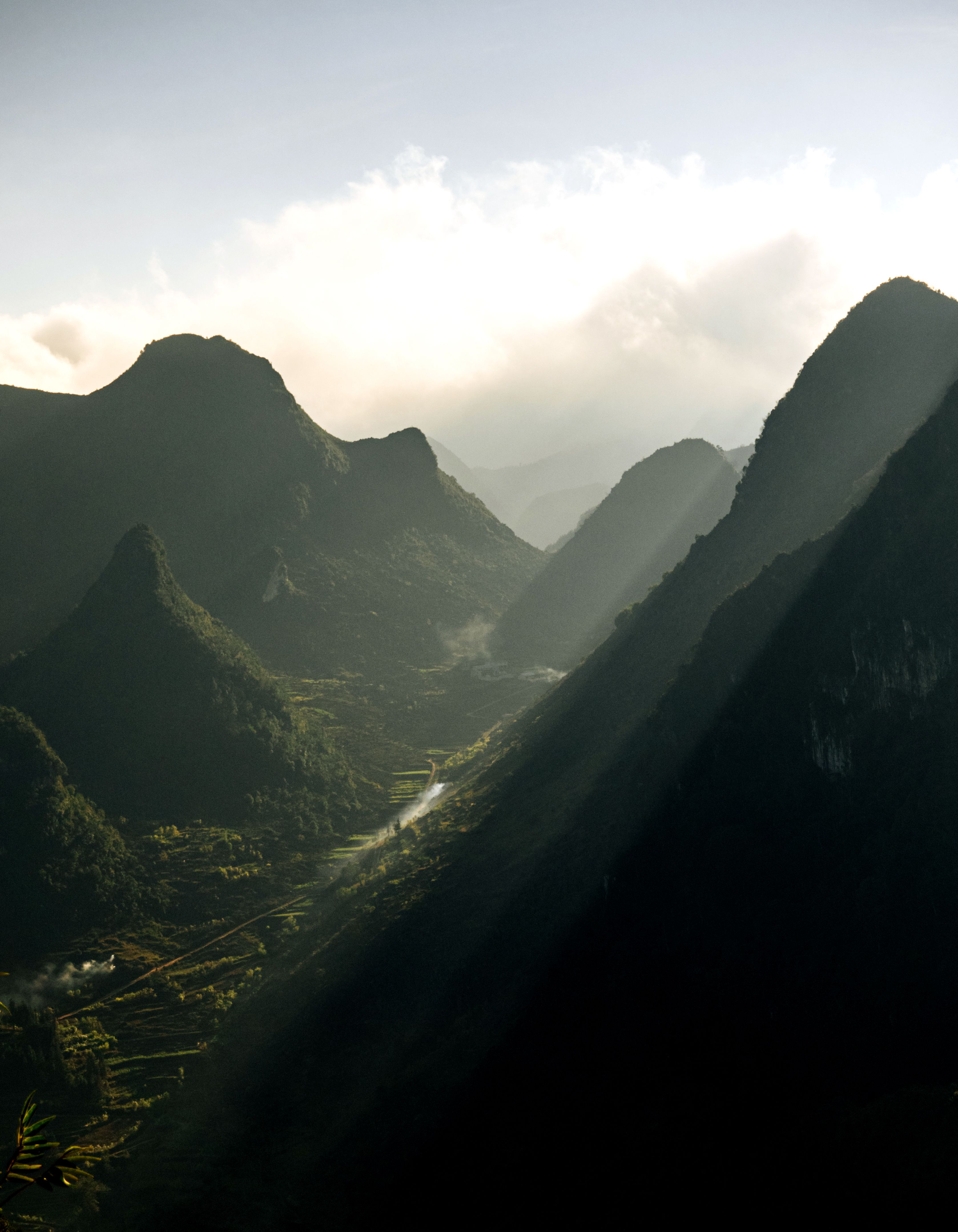 Breathtaking view of sunlit misty mountains with dramatic shadows and lush valleys.