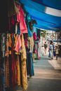 户外市场色彩缤纷，展示了悬挂的衣服和热闹的街头生活