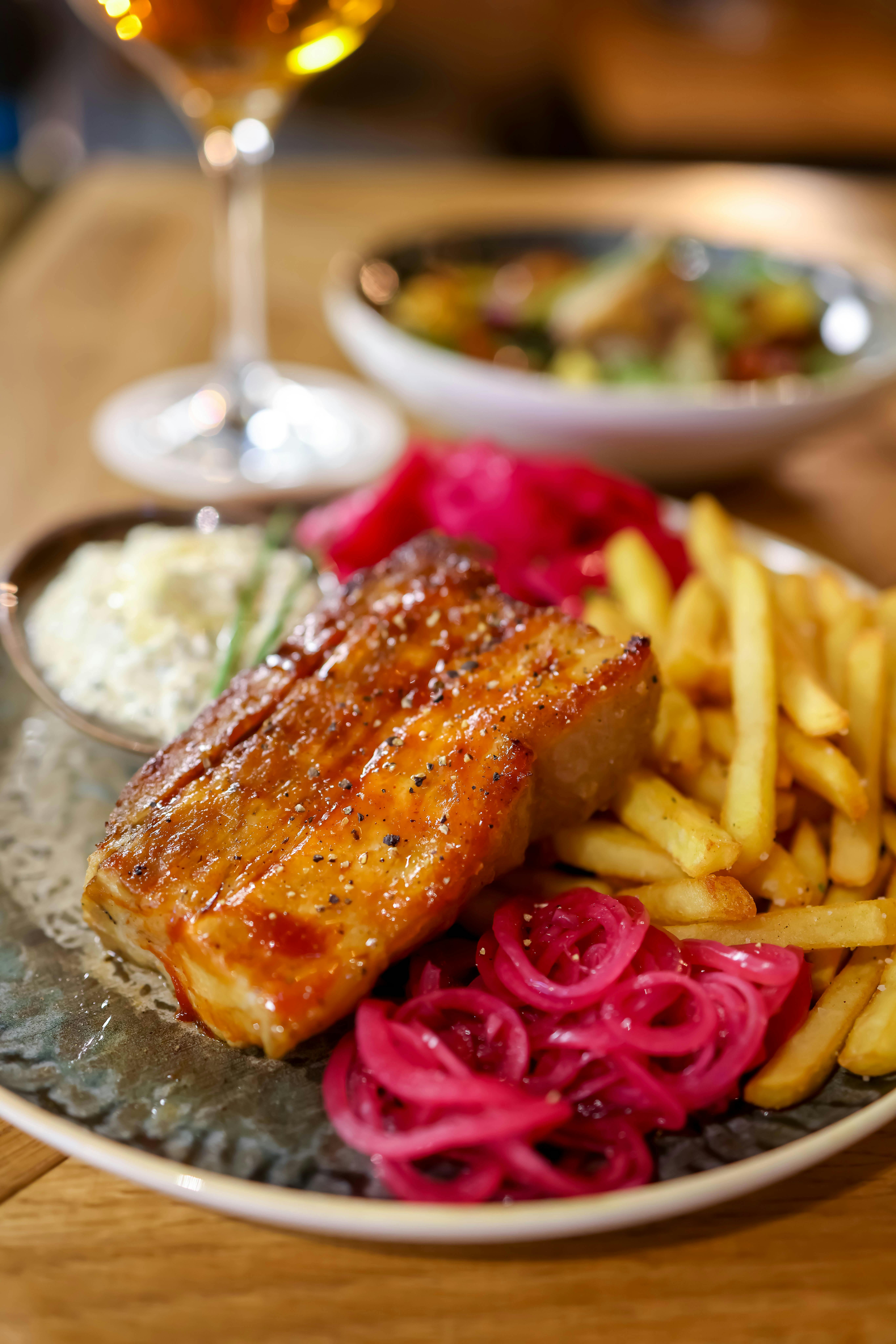 Free Mouthwatering pork belly with french fries and salad, served with wine. Stock Photo