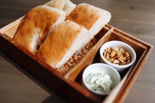 Wooden lunchbox with fresh bread and nuts for a healthy meal alternative.