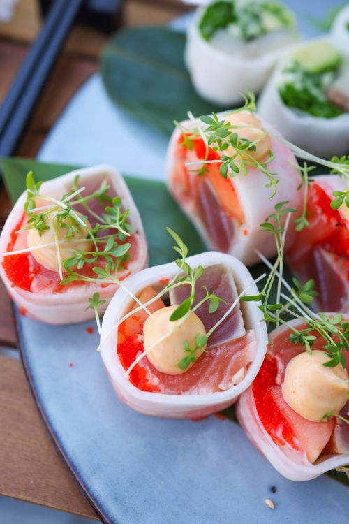 Free Delicious sashimi rolls topped with microgreens and sauce, expertly plated. Stock Photo