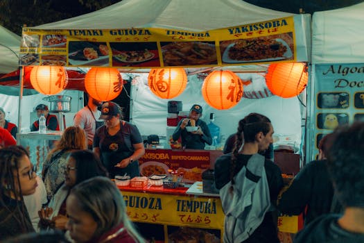 Bustling Asian street food market stall with illuminated lanterns and diverse crowd.
