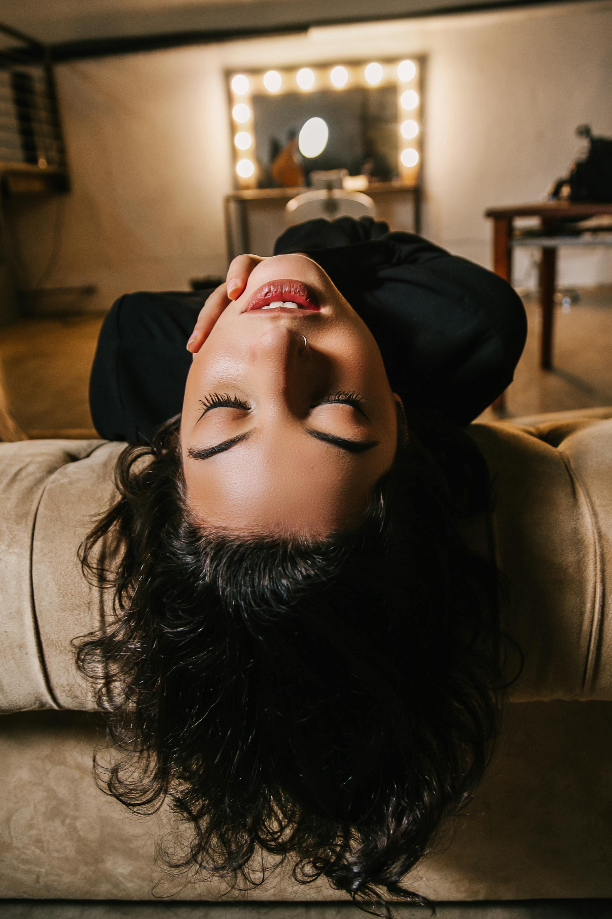 一位轻松的女人躺在客厅温暖的灯光下的沙发上，散发着平静与优雅