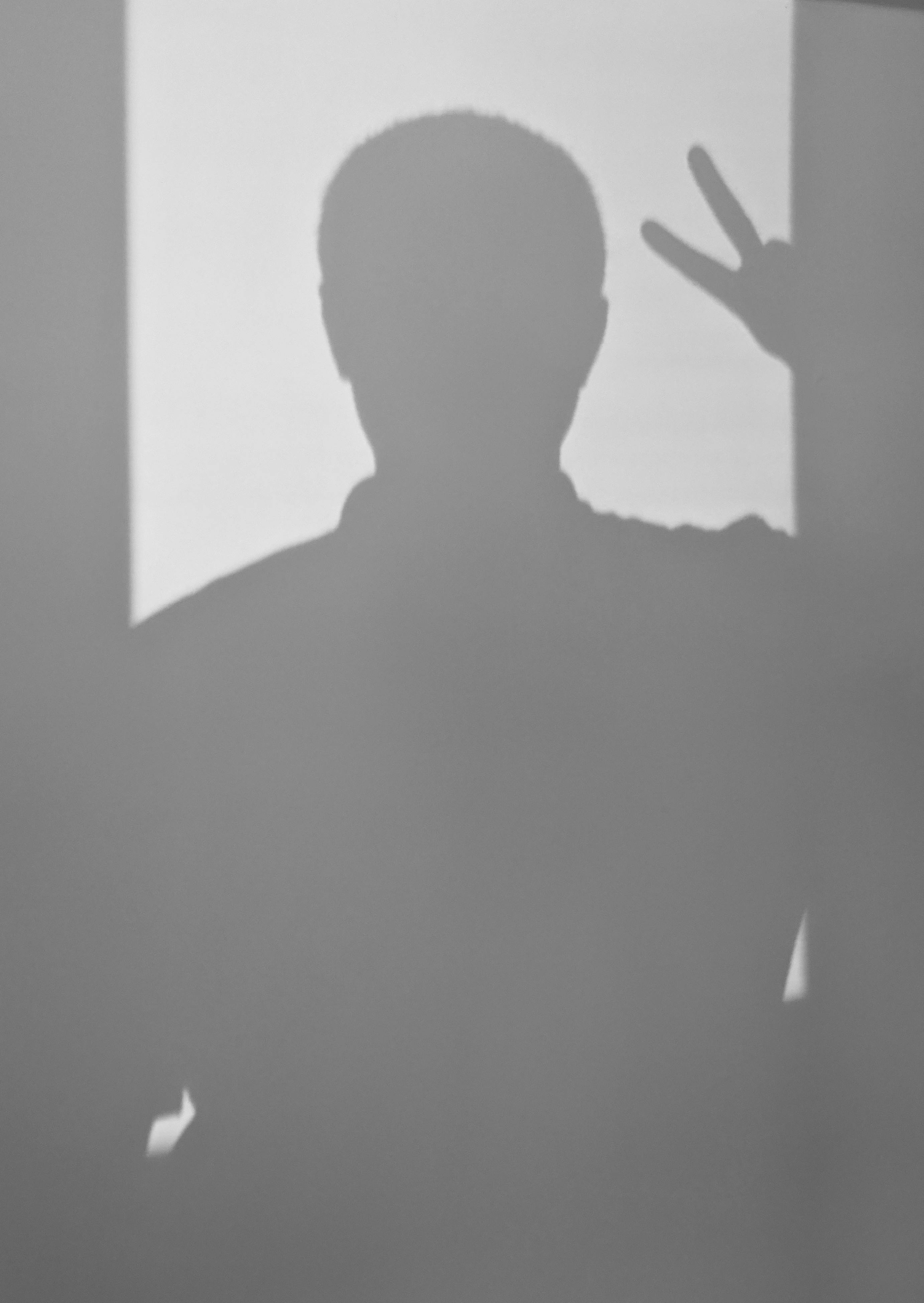 Kostnadsfria Shadow Of Man På Vit Vägg Som Visar V Tecken Stock foto