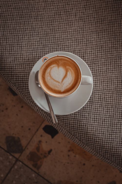 Free A cappuccino with heart-shaped latte art served on a table, perfect for coffee lovers. Stock Photo