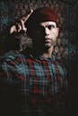 一名戴着贝雷帽和格子衬衫的男子，在喜怒无常的灯光下，摆出自信的姿势