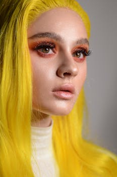 Close-up portrait of a woman with bright yellow hair and bold makeup, exuding artistic flair.