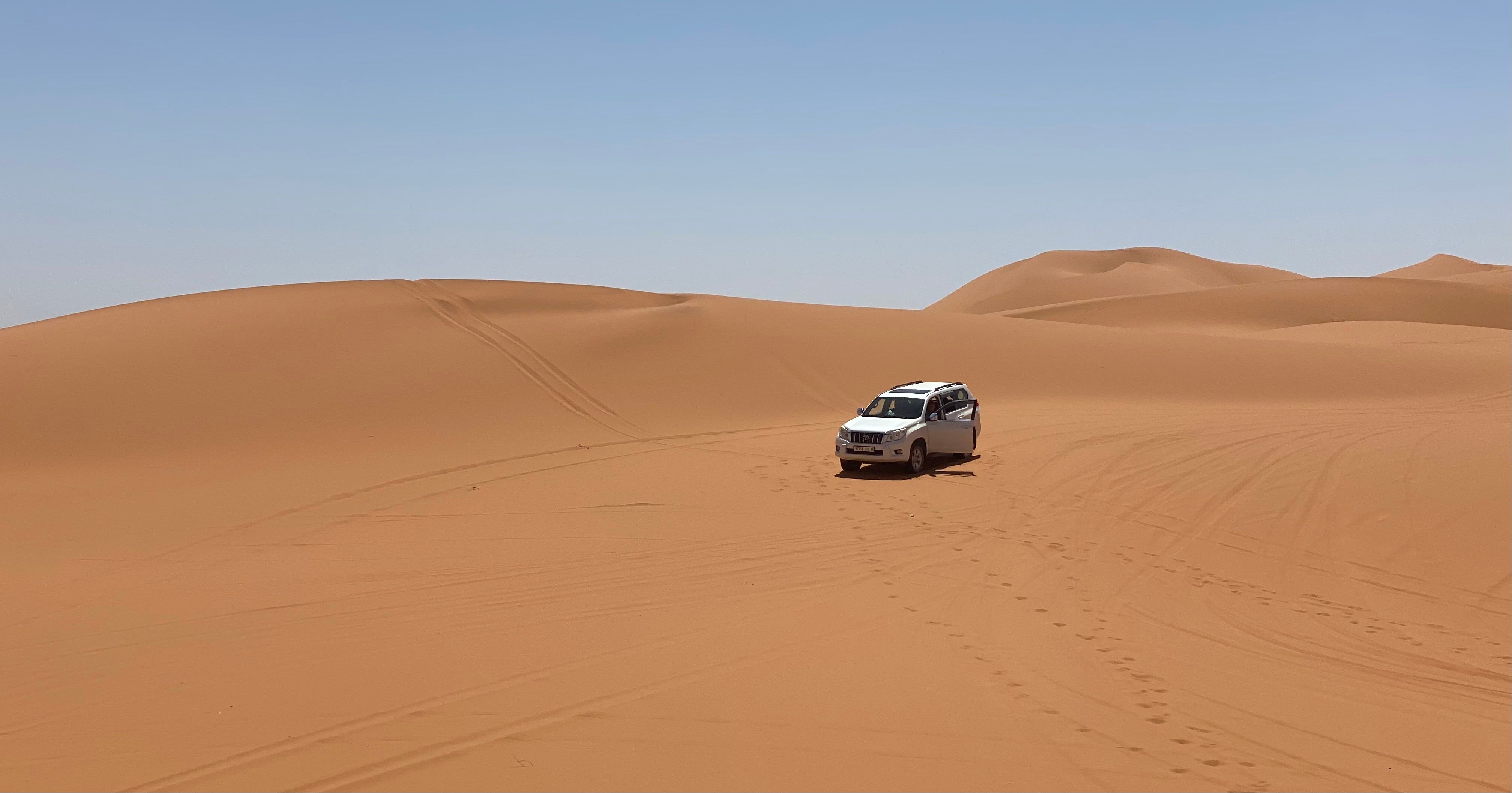 A car driving through the desert with sand dunes · Free Stock Photo