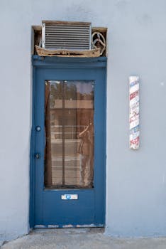 A blue door with an air conditioner above, reflecting an urban street scene in Mojave, CA.