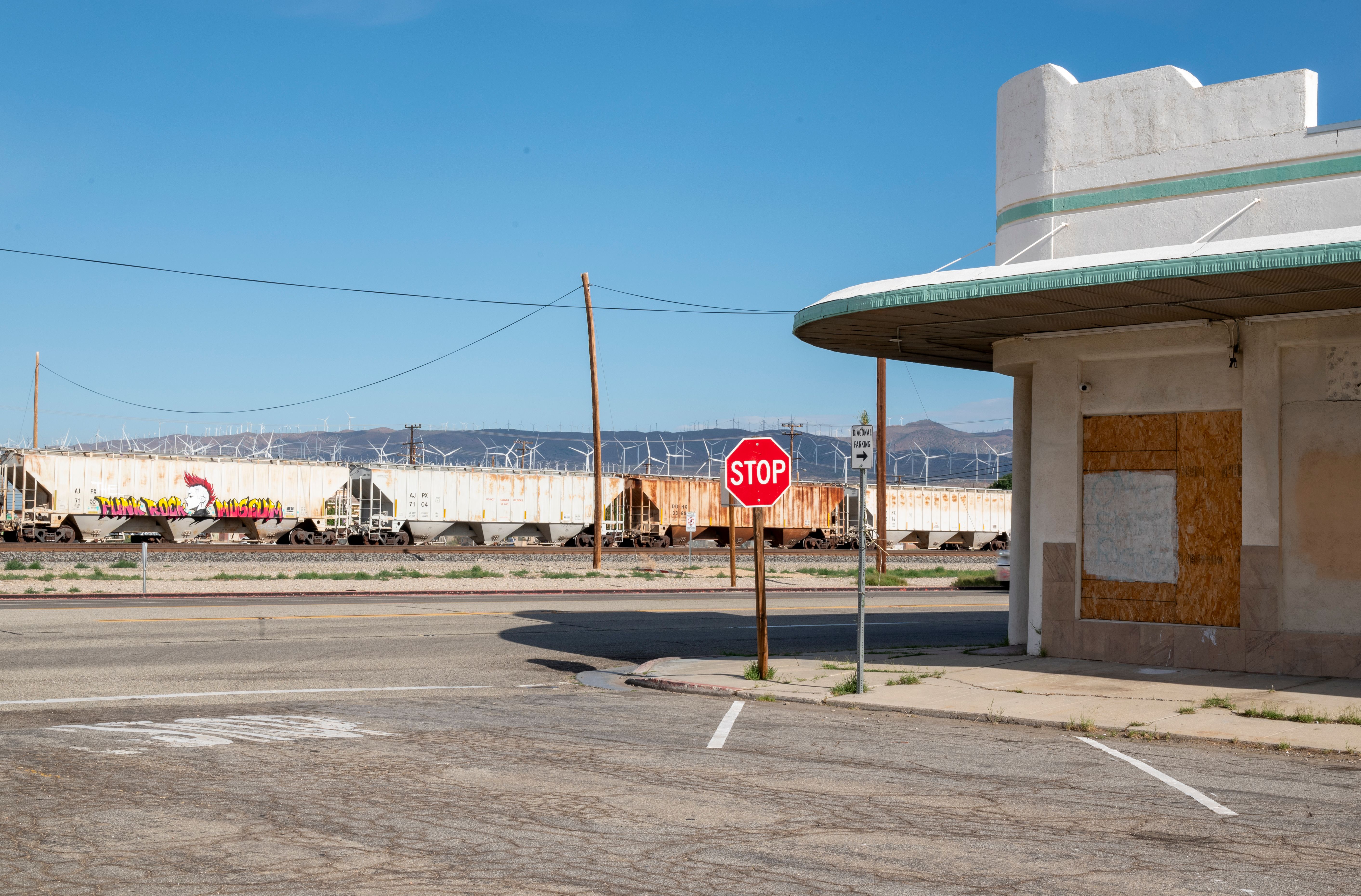 A stop sign beside an abandoned building and train in Mojave, CA.