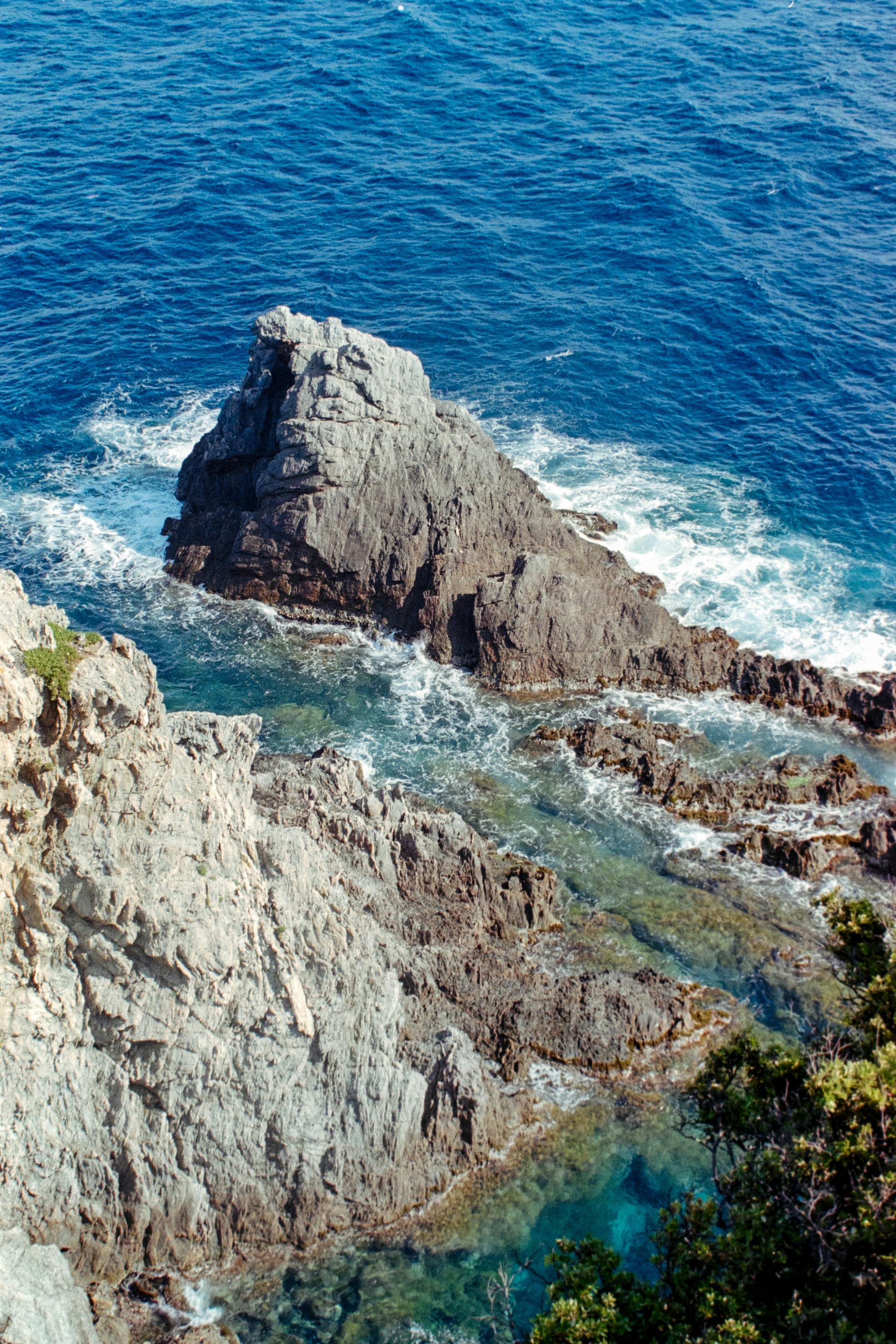Aerial view of rugged coastal cliffs and vibrant blue sea with rock formations.