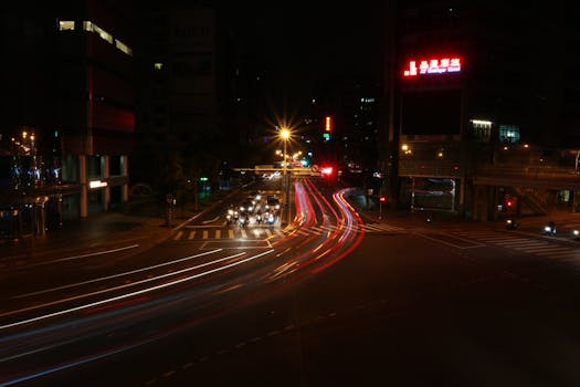 Dynamic city street at night with light streaks from vehicles in long exposure.