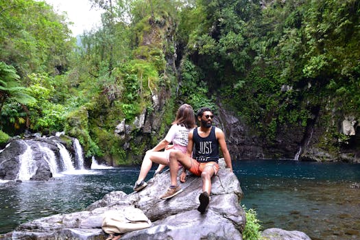 一对夫妇在绿树成荫的瀑布旁，坐在岩石上享受着宁静的时刻