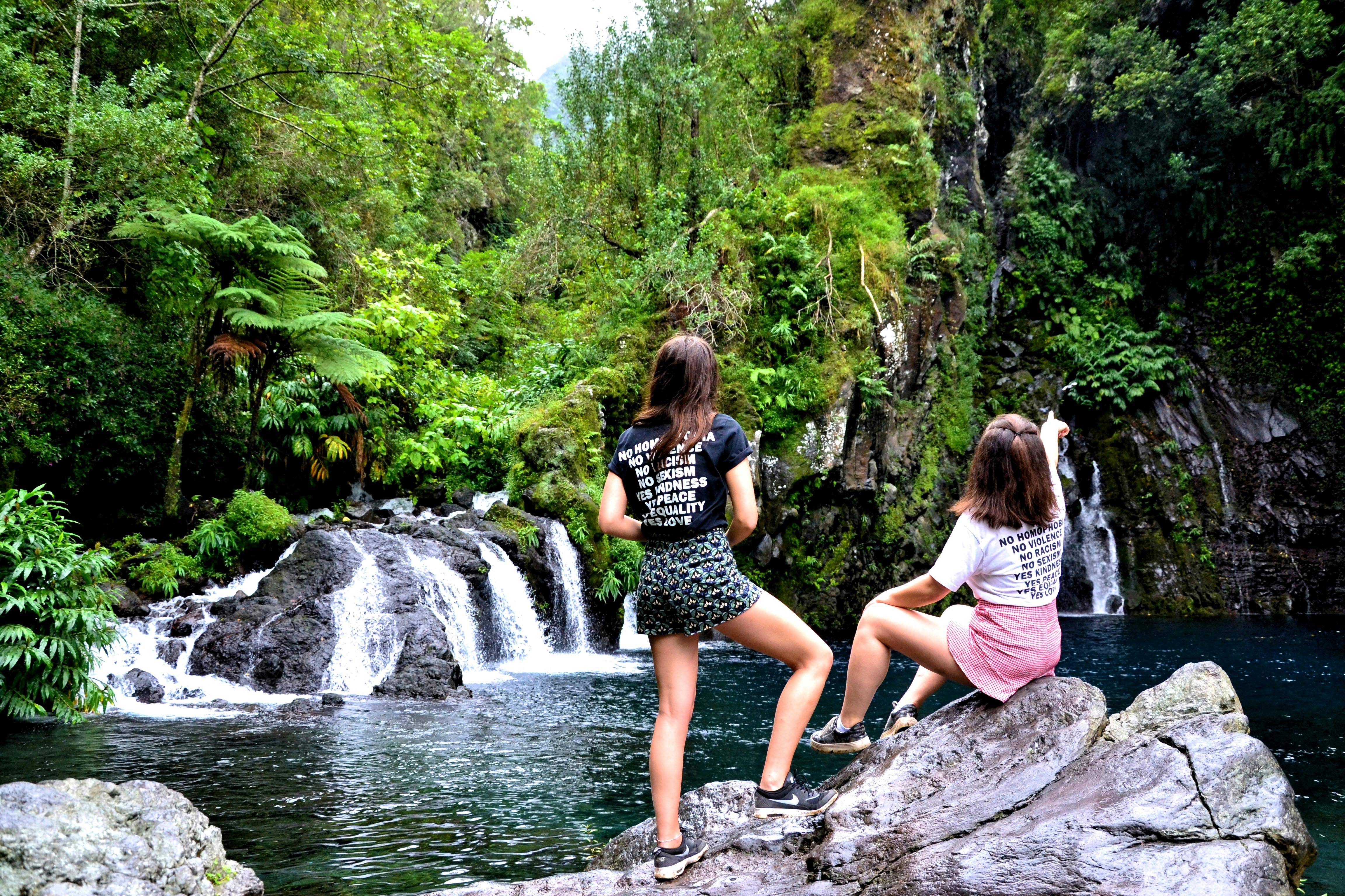 两名女子正欣赏着被郁郁葱葱的绿植环绕的瀑布壮丽景色
