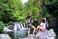 两名女子正欣赏着被郁郁葱葱的绿植环绕的瀑布壮丽景色